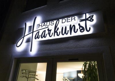 Salon Außenansicht leuchtendes Logo Haus der Haarkunst Haag